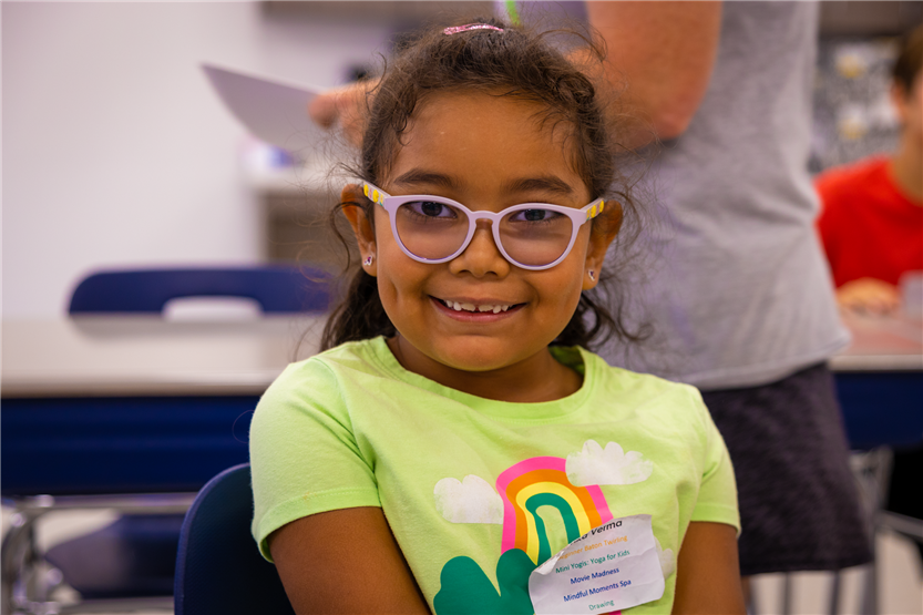 A girl wearing a yellow shirt smiles